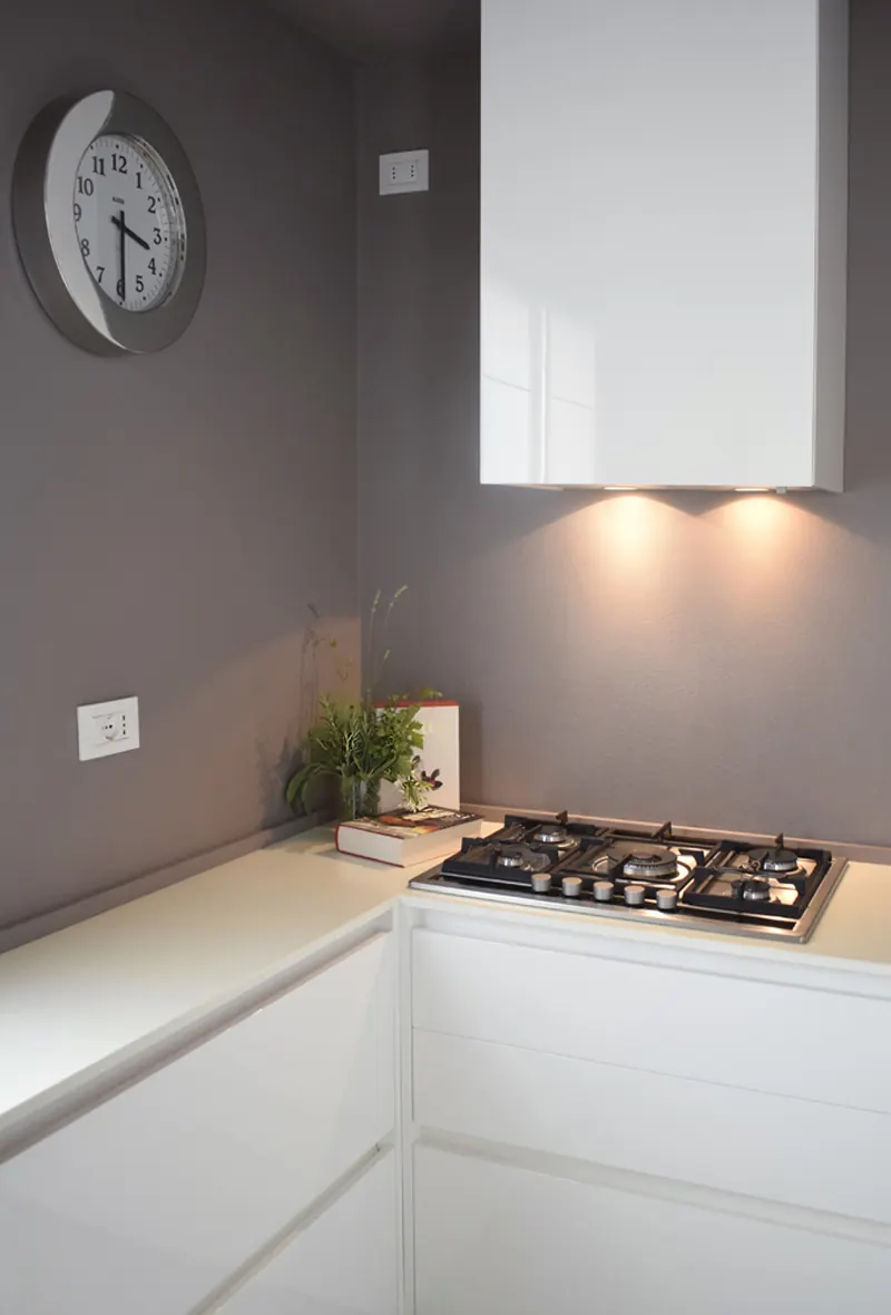 Cucina bianca lucida ad angolo con piano cottura a gas